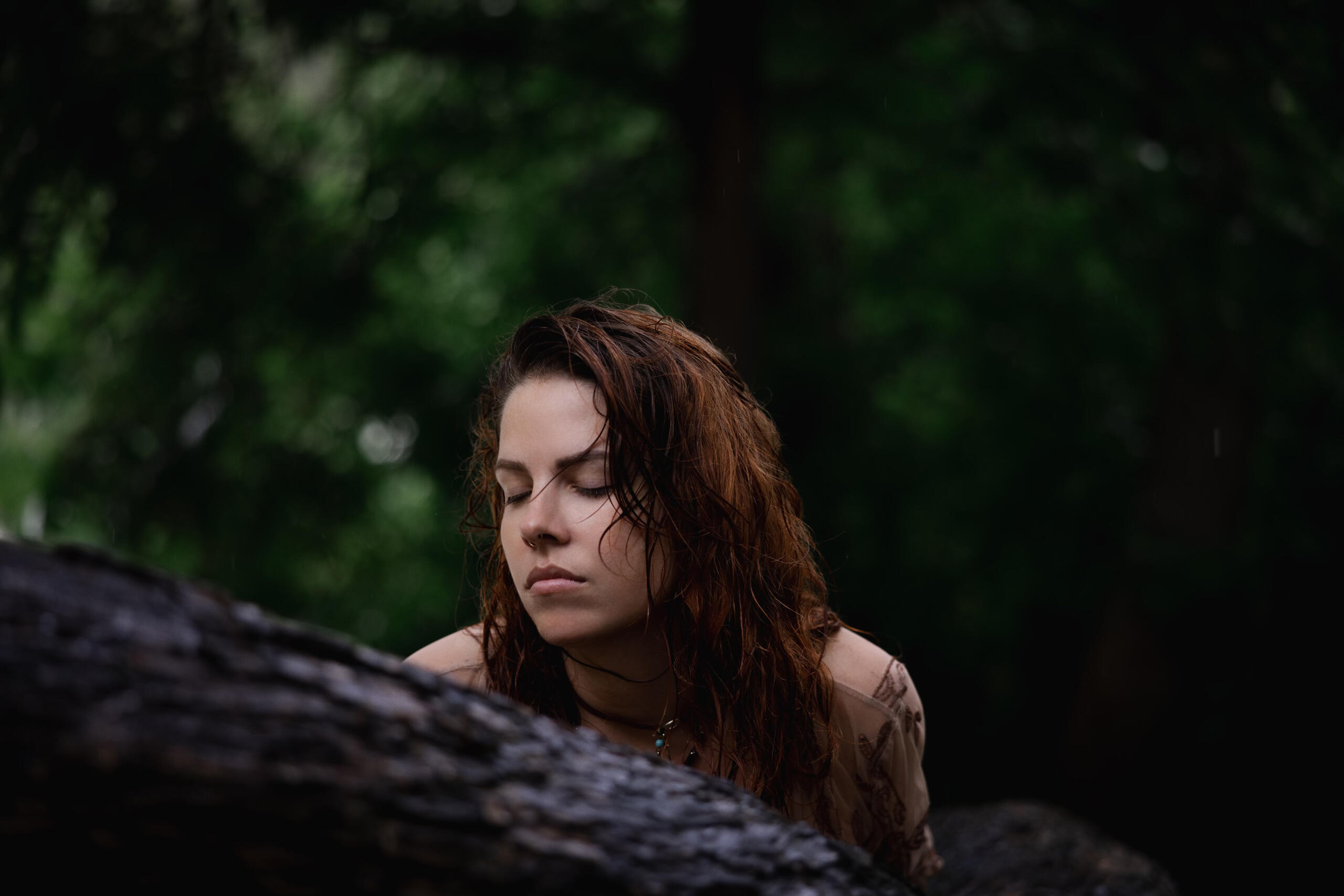 Paige resting against a fallen log in the forest