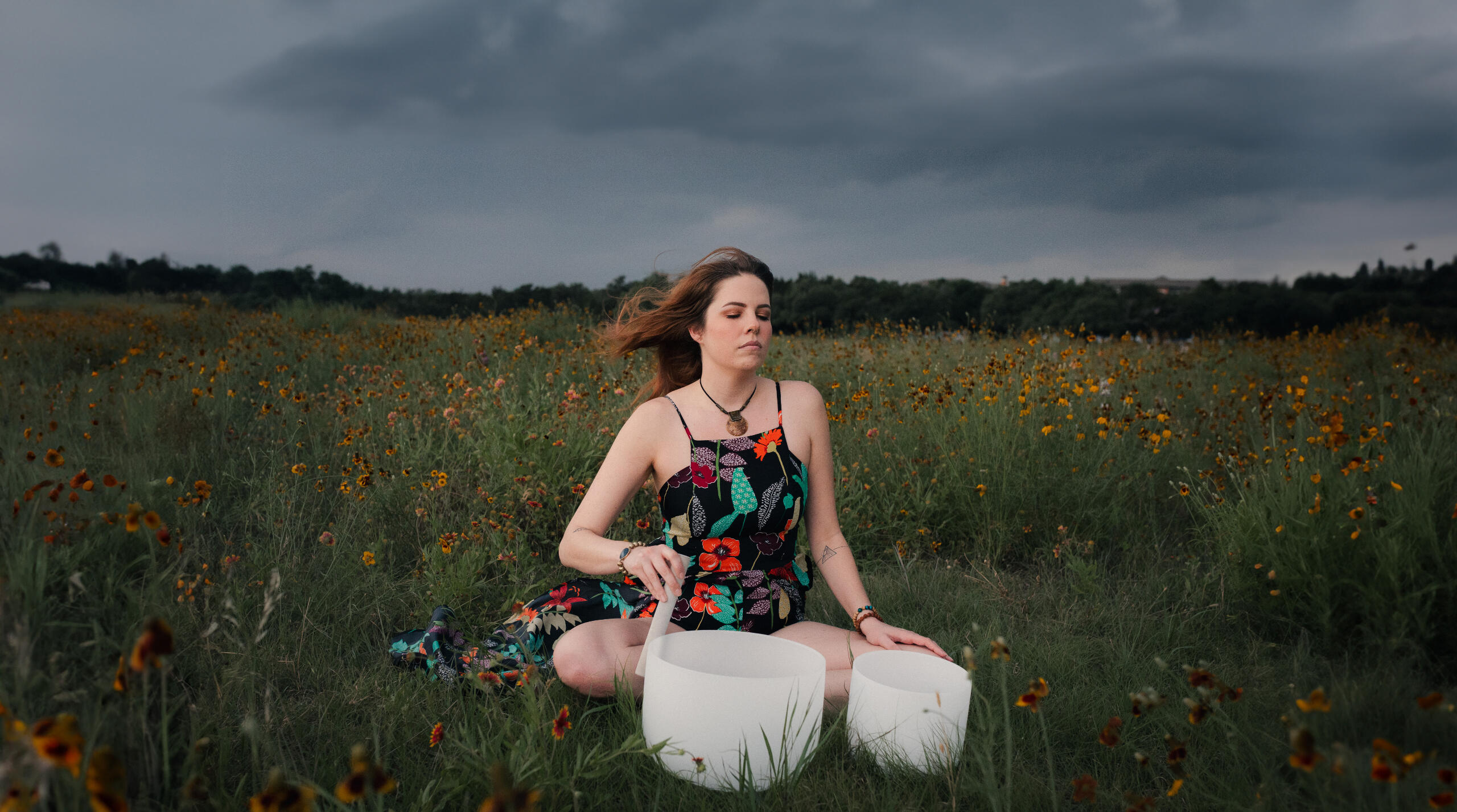 Paige in a Texas wildflower field with crystal sound bowls at dusk